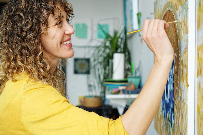 Leah painting acrylic on wood while happy and smiling